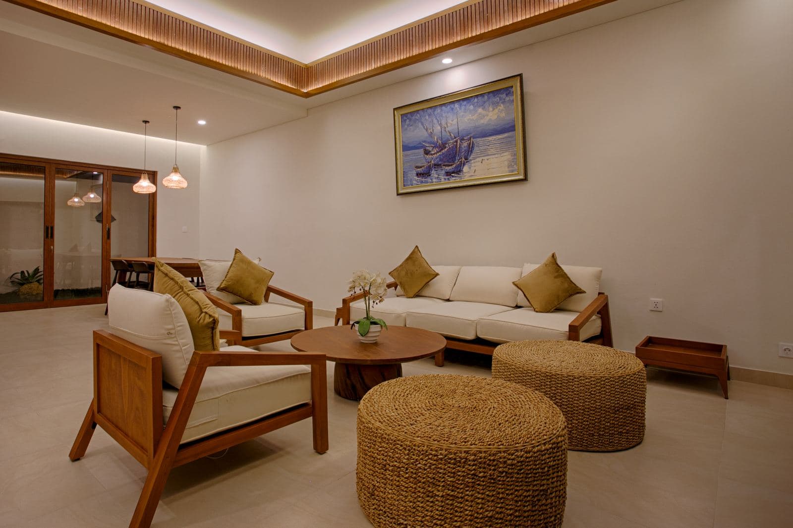 The same living room from the other end: cream armchairs and a corner sofa under a slatted timber ceiling with concealed lighting