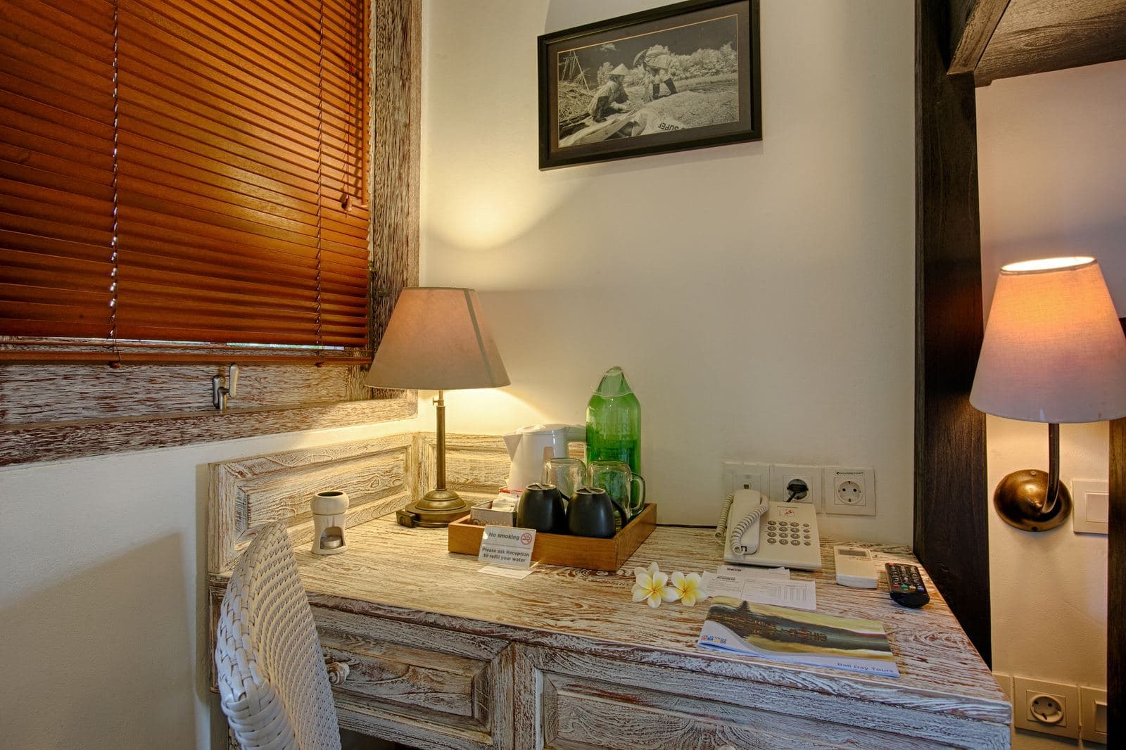 Guest room detail: a driftwood desk with a lamp, tea tray and telephone, and a black and white diving photograph on the wall